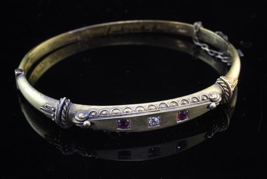 A late Victorian 15ct gold and three stone ruby and diamond set hinged bangle, gross 8.8 grams.